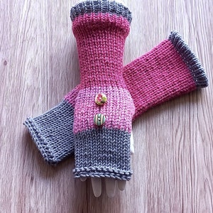 May include: A pair of fingerless gloves with a pink and grey striped pattern. The gloves have two buttons on the wrist.