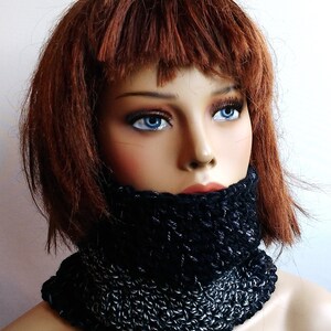 May include: A black and silver crocheted neck warmer. The neck warmer is made with a chunky yarn and has a simple, modern design.