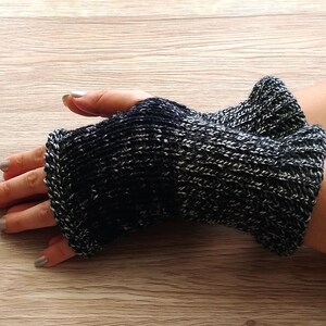 May include: Black and white knit fingerless gloves with a textured pattern.