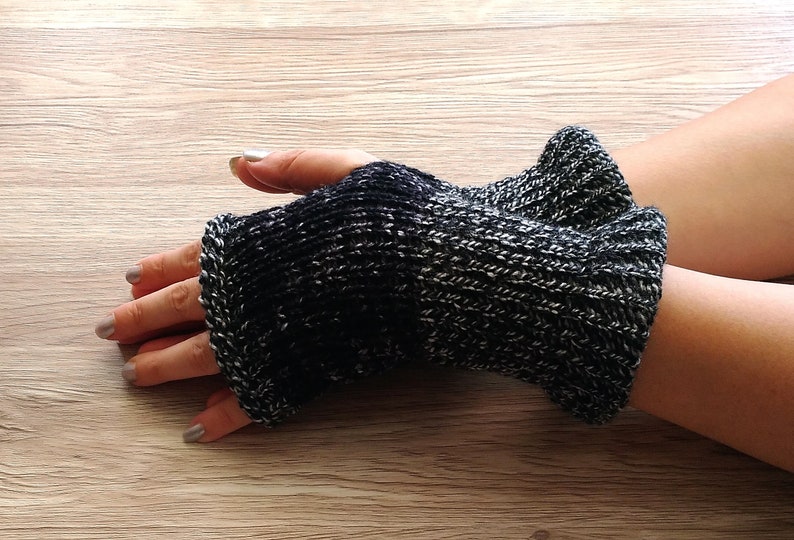 May include: Black and white knit fingerless gloves with a textured pattern.