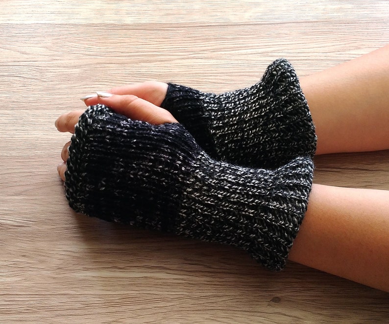 May include: A pair of black and grey fingerless gloves made of knitted fabric.