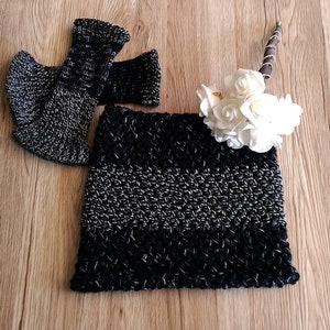 May include: Black and silver crocheted cowl with a striped pattern. The cowl is folded and displayed on a wooden surface.