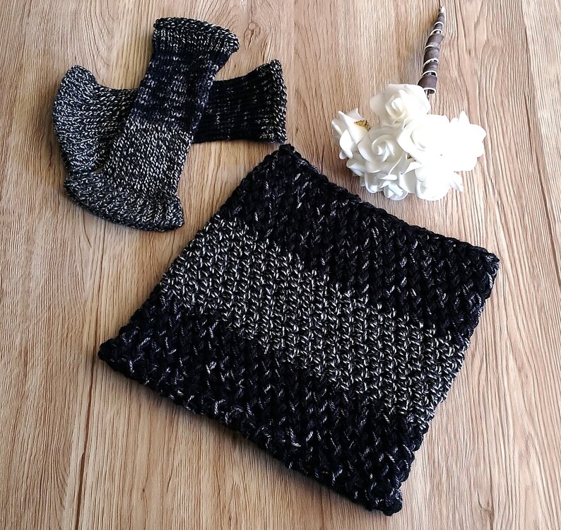 May include: A black and silver knitted neck warmer with a chevron pattern. The neck warmer is made of soft yarn and is perfect for keeping warm in the winter.
