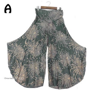 Könnte beinhalten: Grüne weite Hose mit Blumenmuster. Die Hose hat eine weite, fließende Silhouette und eine hohe Taille.