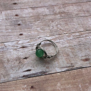 Puede incluir: Un anillo de alambre plateado con una piedra preciosa verde.