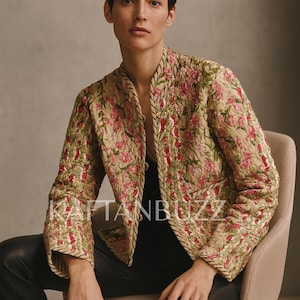 May include: A floral embroidered jacket with pink and green detailing. The jacket features a quilted design and gold trim. The text "KAFTANBUZZ" is visible. The jacket is worn with black trousers.