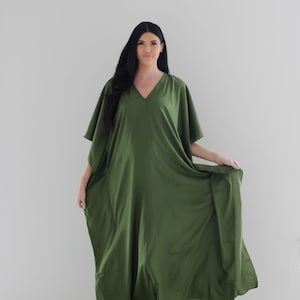 May include: A long, flowing green kaftan dress with a V-neckline and short sleeves. The dress is made of a soft, lightweight fabric and has a relaxed fit.