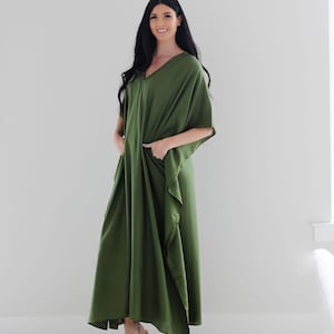 May include: A long, flowing green maxi dress with a V-neck and short sleeves. The dress has a relaxed fit and features pockets on the sides.