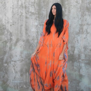 Puede incluir: Una mujer lleva un vestido largo de kaft&aacute;n de color naranja y azul con estampado tie-dye. El vestido tiene un corte holgado y fluido, ideal para un look casual de verano. El vestido est&aacute; hecho de una tela suave y c&oacute;moda, perfecto para un d&iacute;a en la playa o una noche de fiesta con amigos. El vestido est&aacute; disponible en una variedad de colores y tallas.