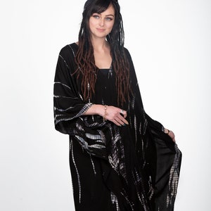 May include: A black and white tie-dye kimono with long sleeves and a V-neck. The kimono is made of a soft, flowing fabric and has a relaxed fit.