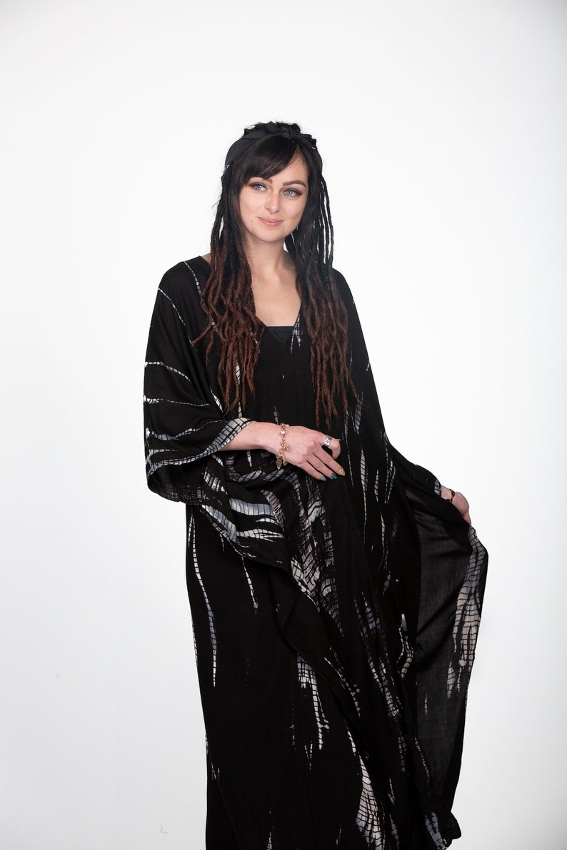 May include: A black and white tie-dye kimono with long sleeves and a V-neck. The kimono is made of a soft, flowing fabric and has a relaxed fit.