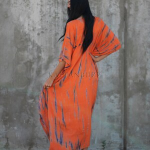 Puede incluir: Un vestido largo de kaft&aacute;n de color naranja y azul con estampado tie-dye y escote en V. El vestido tiene un corte holgado y fluido, perfecto para un look casual de verano.