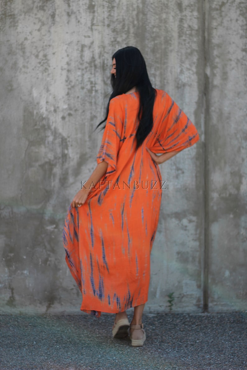 Puede incluir: Un vestido largo de kaft&aacute;n de color naranja y azul con estampado tie-dye y escote en V. El vestido tiene un corte holgado y fluido, perfecto para un look casual de verano.