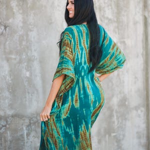 May include: A long, flowing teal and brown tie-dye maxi dress with a V-neckline and wide sleeves.