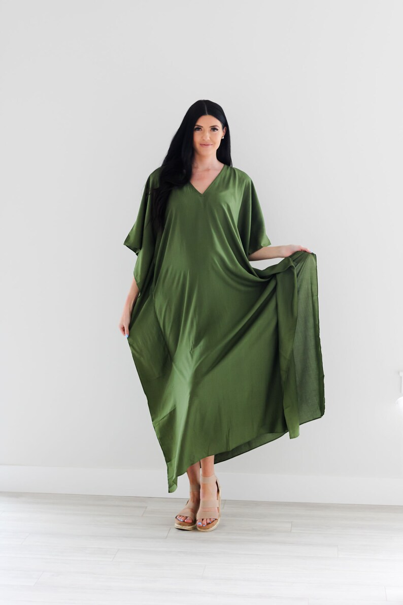 May include: A long, flowing green maxi dress with a V-neck and short sleeves. The dress is made of a soft, silky fabric and has a relaxed fit.