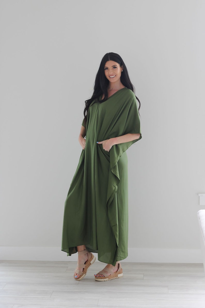 May include: A long, flowing green maxi dress with a V-neck and short sleeves. The dress has a relaxed fit and is made of a soft, comfortable fabric.