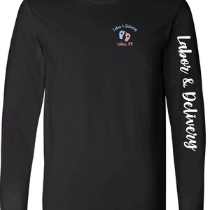 May include: Black long-sleeve t-shirt with white text on the sleeve that reads "Labor & Delivery". The front of the shirt has a small graphic of two footprints, one blue and one pink, with the text "Labor & Delivery" and "Esther, RN".