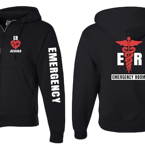 May include: Black zippered hoodie with a red heart and the text "ER Jessica" on the left side, the text "EMERGENCY" on the right sleeve, and a red medical symbol with the text "ER EMERGENCY ROOM" on the back.