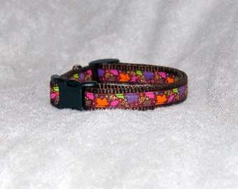 May include: A brown dog collar with a colorful pattern of leaves and flowers. The collar has a black plastic buckle.