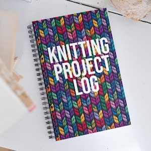 Può includere: Un taccuino a spirale con una copertina a fantasia a maglia colorata. La copertina presenta un motivo ripetuto di fili blu, viola, verdi, arancioni e gialli. Il testo bianco recita "KNITTING PROJECT LOG".