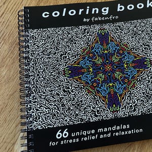 Könnte beinhalten: Ein quadratisches Malbuch mit Spiralbindung von fabenfro mit schwarzem Einband und einem farbigen Mandala-Motiv in der Mitte. Der Einbandtext lautet coloring book, 66 unique mandalas for stress relief and relaxation sowie 21 x 21 cm.