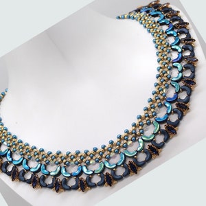 Könnte beinhalten: Eine blaue und goldene Perlenkette mit geometrischem Muster. Die Kette besteht aus kleinen, runden Perlen und größeren, halbmondförmigen Perlen.