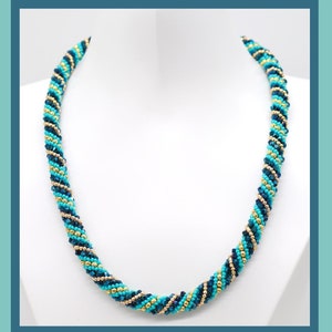 May include: A turquoise, gold, and dark blue beaded necklace with a spiral design.