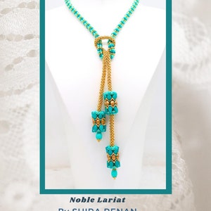 Puede incluir: Un collar de cuentas turquesa y dorado con un diseño anudado y tres cilindros de cuentas colgantes. El collar se llama "Noble Lariat" de Shira Renan.