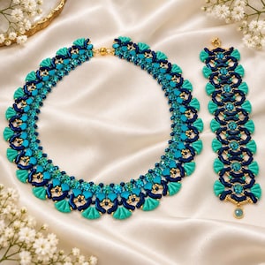 May include: A beaded necklace and matching bracelet set featuring a complex woven pattern of dark navy blue and bright turquoise fan-shaped beads, interspersed with sparkling light blue crystals and small gold-toned metallic accent beads.