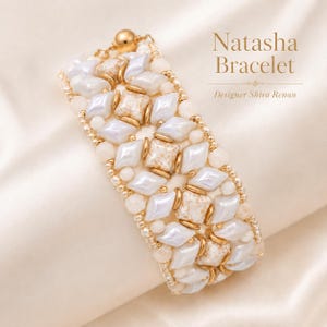 Puede incluir: La pulsera Natasha de la diseñadora Shira Renan presenta un patrón tejido de cuentas blancas en forma de diamante, cuentas cuadradas de color beige jaspeado y pequeñas cuentas espaciadoras metálicas doradas con cierre esférico.