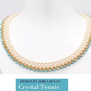 May include: A white and blue beaded necklace with a gold accent. The necklace is made with small, round beads and has a delicate, feminine look. The text "DESIGN BY SHIRA RENAN Crystal Tennis" is displayed below the necklace.