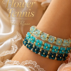 May include: Three stacked bracelets featuring flower-shaped beads in shades of light blue, turquoise, and dark teal, accented with small gold-toned beads. The text "Flower Tennis" and "Shira Renan" is visible in the upper left corner of the image.
