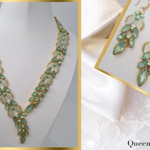 Op de afbeelding: Een ketting- en oorbellenset met een bladvormgeving. De ketting en oorbellen hebben lichtgroene en witte stenen met goudkleurige metalen accenten. De ketting wordt getoond op een witte mannequin.