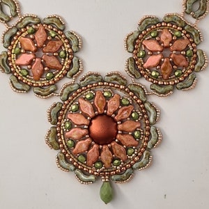 May include: A beaded necklace with three circular pendants. The pendants are made of copper, green, and peach colored beads. The center pendant is larger than the other two.