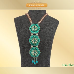 Może przedstawiać: Naszyjnik z turkusowych i białych koralików z trzema kwiatowymi zawieszkami. Naszyjnik jest prezentowany na czarnym manekinie. Pod naszyjnikiem widnieje napis "Iris Flower".