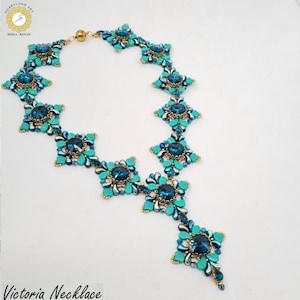 Könnte beinhalten: Eine türkisfarbene und goldfarbene Halskette mit Perlen und einem floralen Design. Die Halskette hat große, dunkelblaue Mittelsteine und ist mit "Victoria Necklace" beschriftet. Die Halskette besteht aus kleinen Perlen und hat einen goldenen Verschluss.