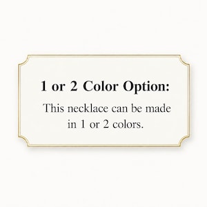 May include: A rectangular sign with a gold border and text that reads "1 or 2 Color Option: This necklace can be made in 1 or 2 colors." The sign is on a white background.