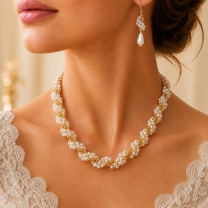 May include: A necklace and a single earring set featuring a twisted design of small white pearls interwoven with gold-toned metal links. The earring consists of a small cluster of pearls attached to a single white teardrop-shaped pearl pendant.