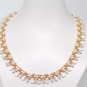 May include: A white and gold beaded necklace with a delicate design. The necklace features small, round gold beads and larger, oval white beads.