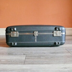 May include: A black hard-sided suitcase with silver metal clasps and a silver metal handle.