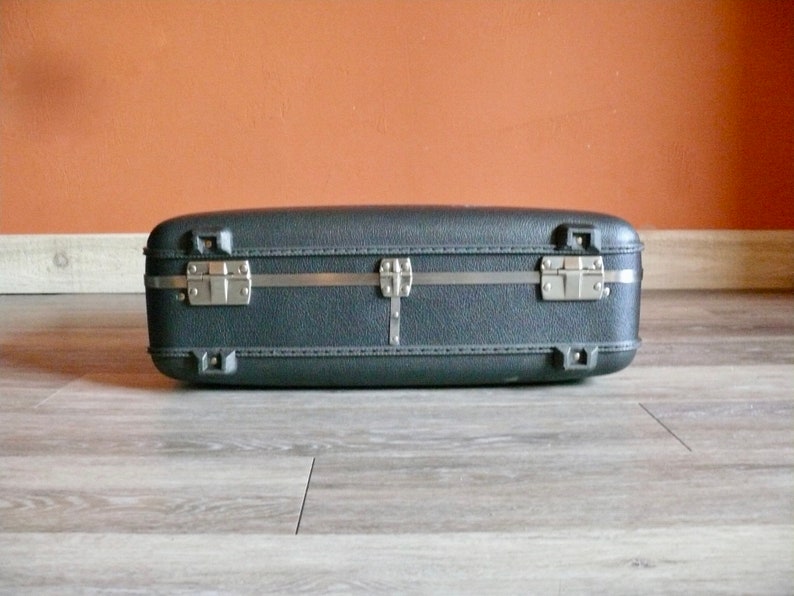 May include: A black hard-sided suitcase with silver metal clasps and a silver metal handle.