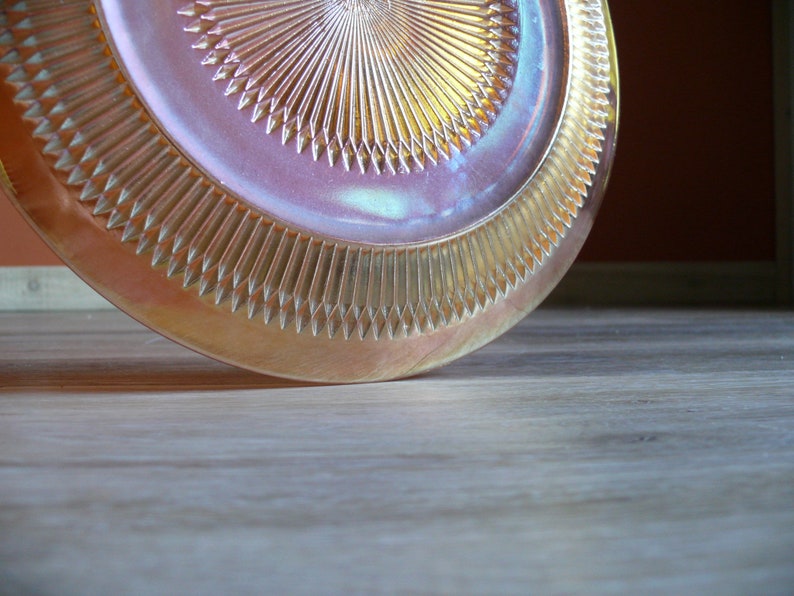 Puede incluir: Un plato de vidrio iridiscente vintage con un patr&oacute;n de diamante. El plato es de color rosa claro con un brillo dorado.