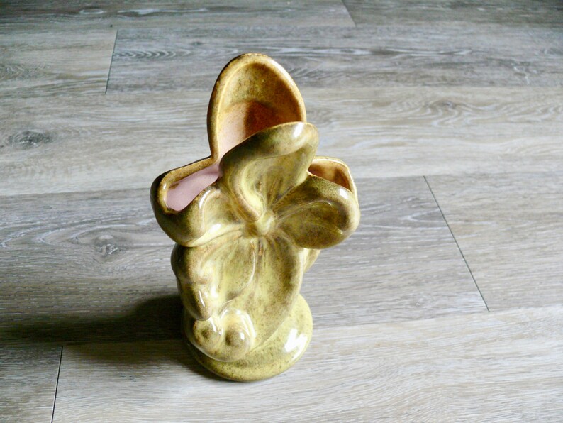 K&ouml;nnte beinhalten: Eine Vintage-Vase aus hellgr&uuml;ner Keramik mit einer einzigartigen, organischen Form. Die Vase hat eine strukturierte Oberfl&auml;che und einen hellrosa Innenraum. Das Design &auml;hnelt einer stilisierten Blume oder einem Blatt und verleiht jedem Raum einen Retro-Charme.