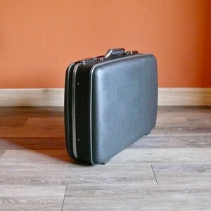 May include: A black vintage suitcase with a silver handle and trim.