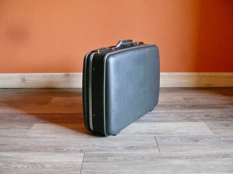 May include: A black vintage suitcase with a silver handle and trim.