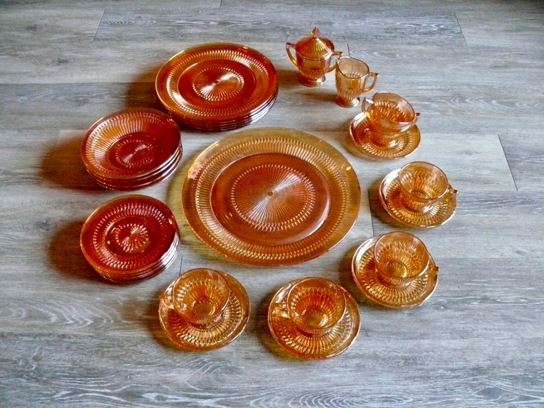 Puede incluir: Un juego de vajilla de vidrio &aacute;mbar, que incluye platos, cuencos y tazas. El juego presenta un patr&oacute;n decorativo en relieve en la superficie de cada pieza.