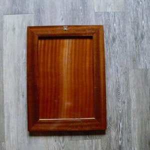 K&ouml;nnte beinhalten: Ein rechteckiger Holzbilderrahmen mit einer dunkelbraunen Oberfl&auml;che. Der Rahmen hat ein schlichtes Design mit einer glatten Oberfl&auml;che.