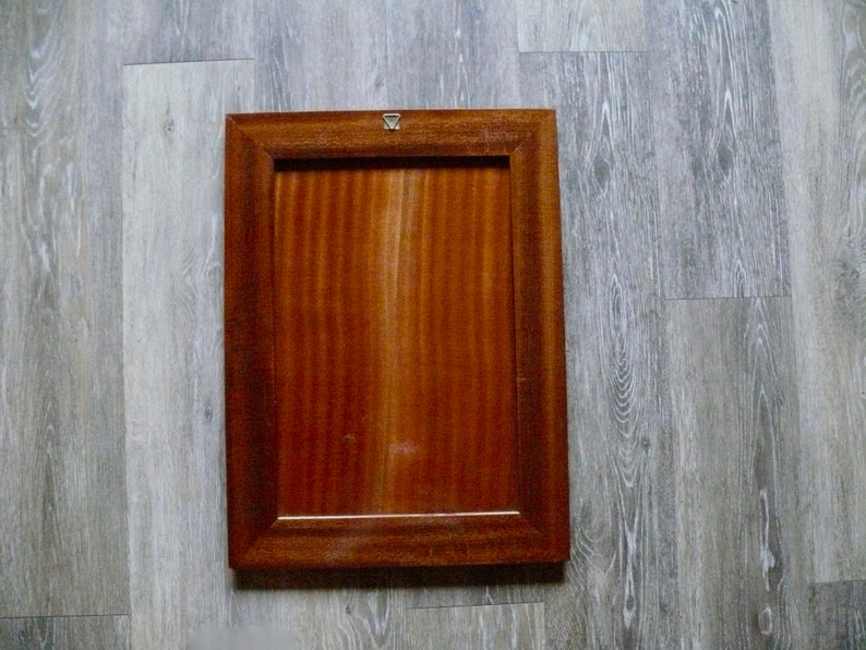 K&ouml;nnte beinhalten: Ein rechteckiger Holzbilderrahmen mit einer dunkelbraunen Oberfl&auml;che. Der Rahmen hat ein schlichtes Design mit einer glatten Oberfl&auml;che.