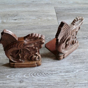 May include: A pair of wooden bookends shaped like fish. The bookends are carved with intricate details and have a dark brown finish.