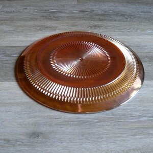 Puede incluir: Un plato grande, redondo, de vidrio &aacute;mbar con un patr&oacute;n decorativo en forma de diamante. El plato tiene una superficie brillante y reflectante.